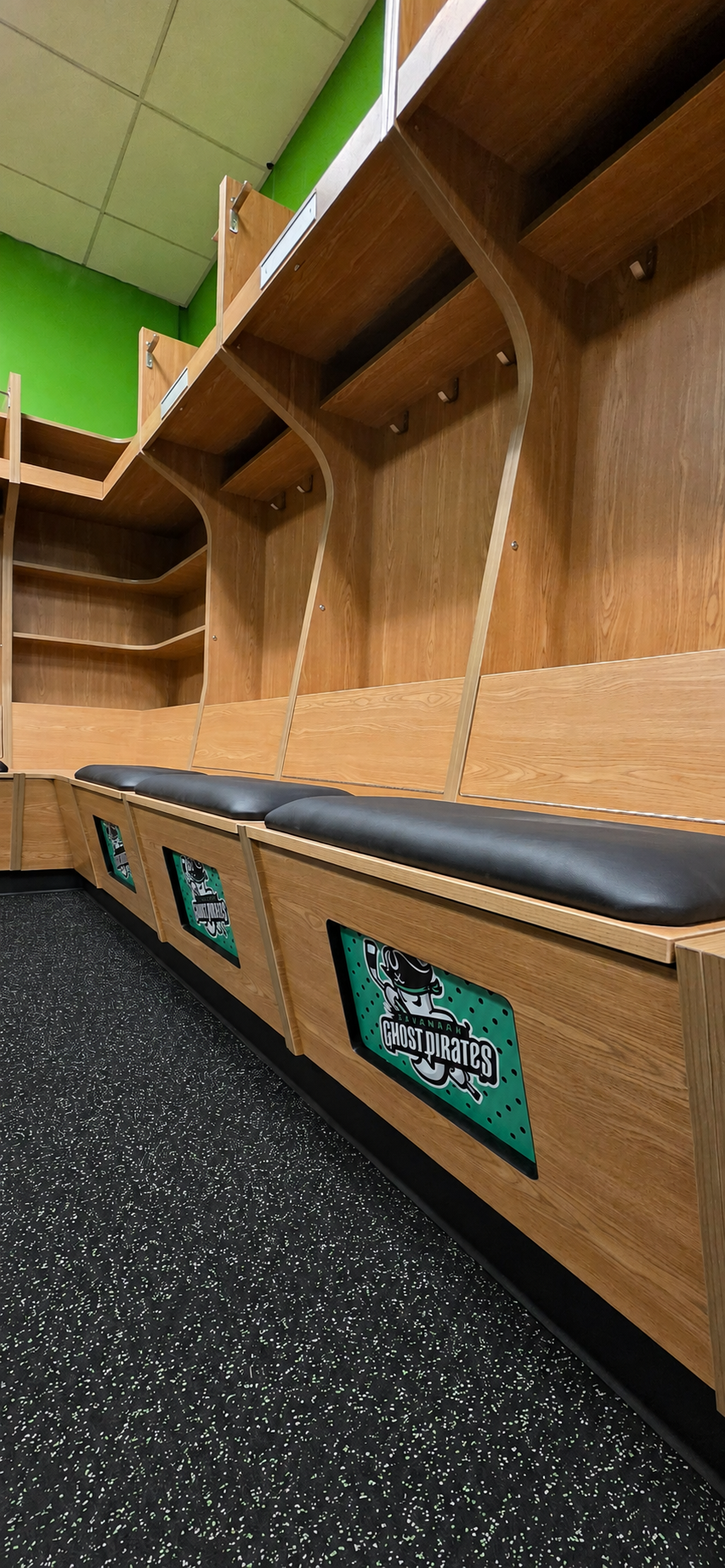 Photo of custom hockey locker room with corner shelf for storage and seat cushion.